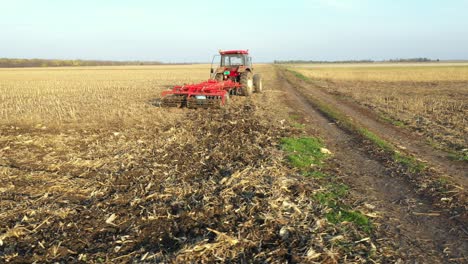 vista lateral aérea de un agricultor raspando la suciedad debajo de una harro de disco en un campo agrícola