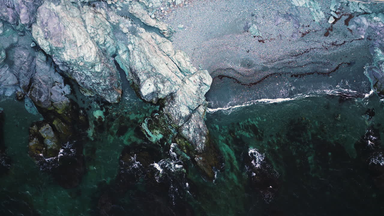 뉴포트의 회색 자갈 모래 해변 에 있는 큰  암석 어리, 드론 상단 아래