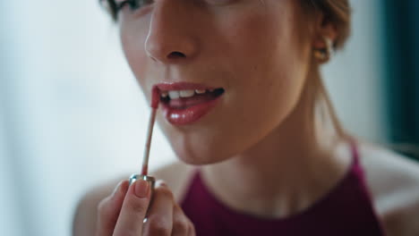 un pincel de primer plano aplicando lápiz labial. una chica romántica haciendo maquillaje admirándose a sí misma.