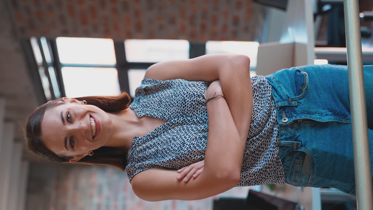 retrato de video vertical de una joven mujer de negocios sonriente en una oficina ocupada