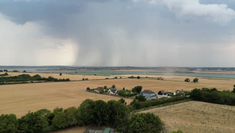 Imágenes-Aéreas-De-Campos-Cosechados-Con-Nubes-De-Lluvia-Y-Ráfagas-De-Lluvia-En-La-Distancia,-Carro-De-Drones-De-Izquierda-A-Derecha