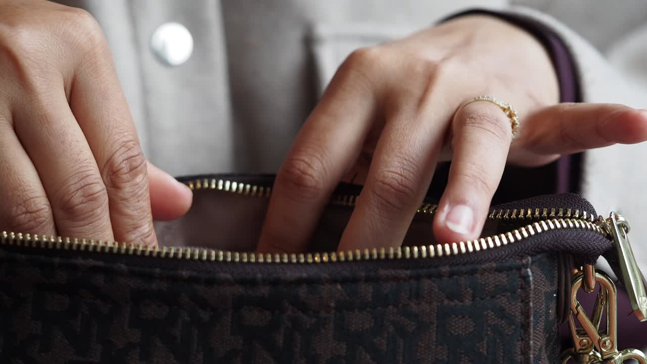 Woman's Hands Opening a Purse to Get a Sanitary Napkin