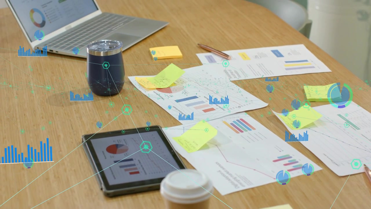 Teal HUD overlay appearing over tabletop charts, tablet laptop, linking devices showing insights