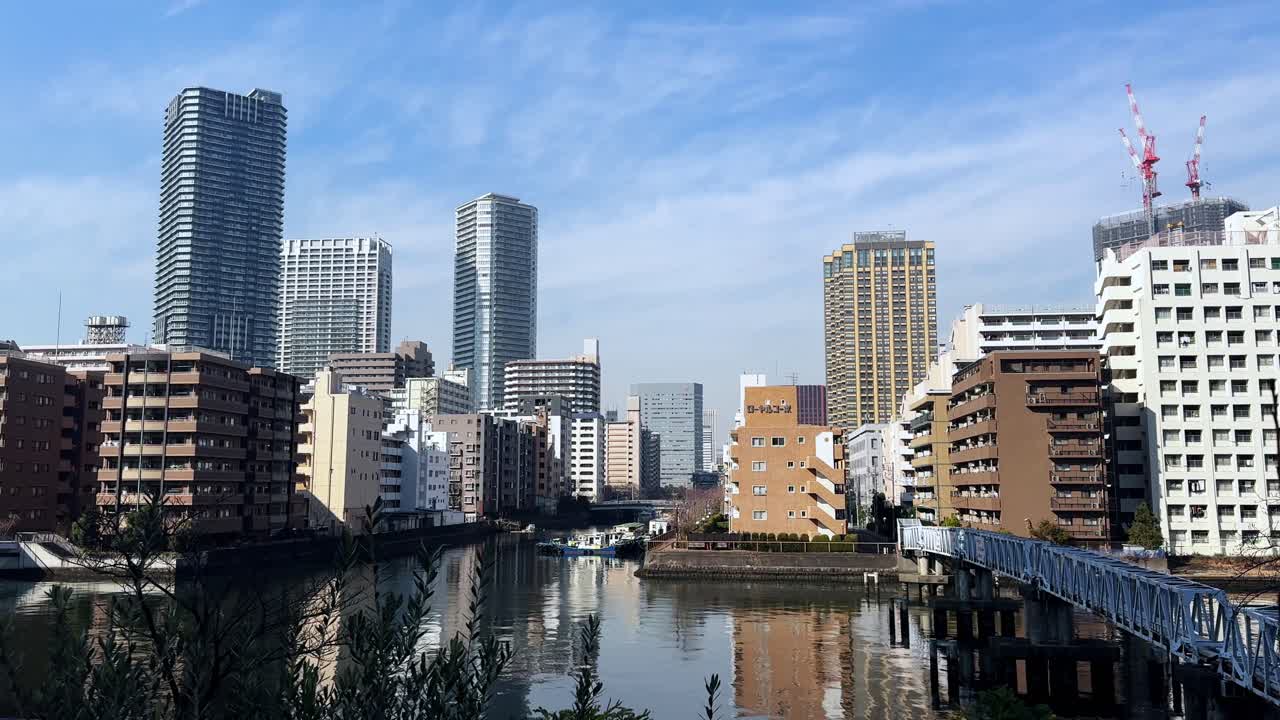 A peaceful cityscape of modern Tokyo skyscrapers reflecting on a calm canal
