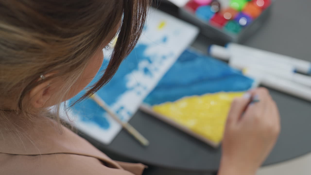 Estudiante pintando un triángulo, estudiante concentrada ilustrando una forma geométrica en un aula, ambiente educativo informal con una niña centrada en su composición artística