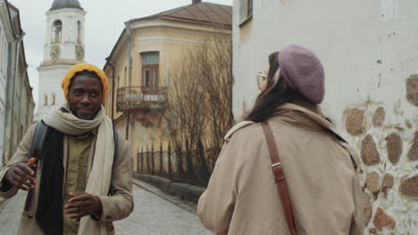 una alegre pareja multiétnica caminando por la ciudad vieja y charlando