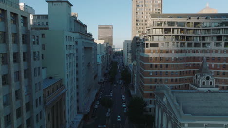 Multistorey-buildings-along-wide-street-in-city-centre.-Backwards-revealing-of-Groote-Kerk-church.-Cape-Town,-South-Africa