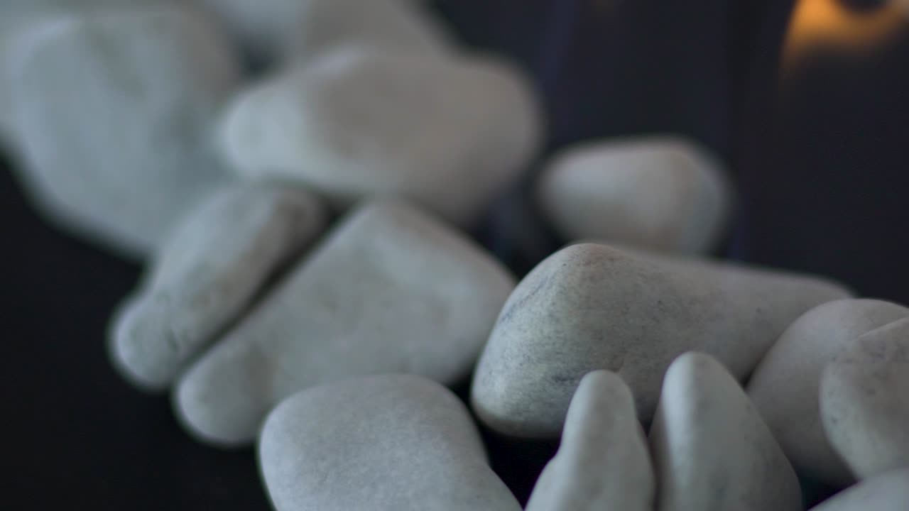 Close up slow motion tracking shot of pebbles with gas fire in-between them