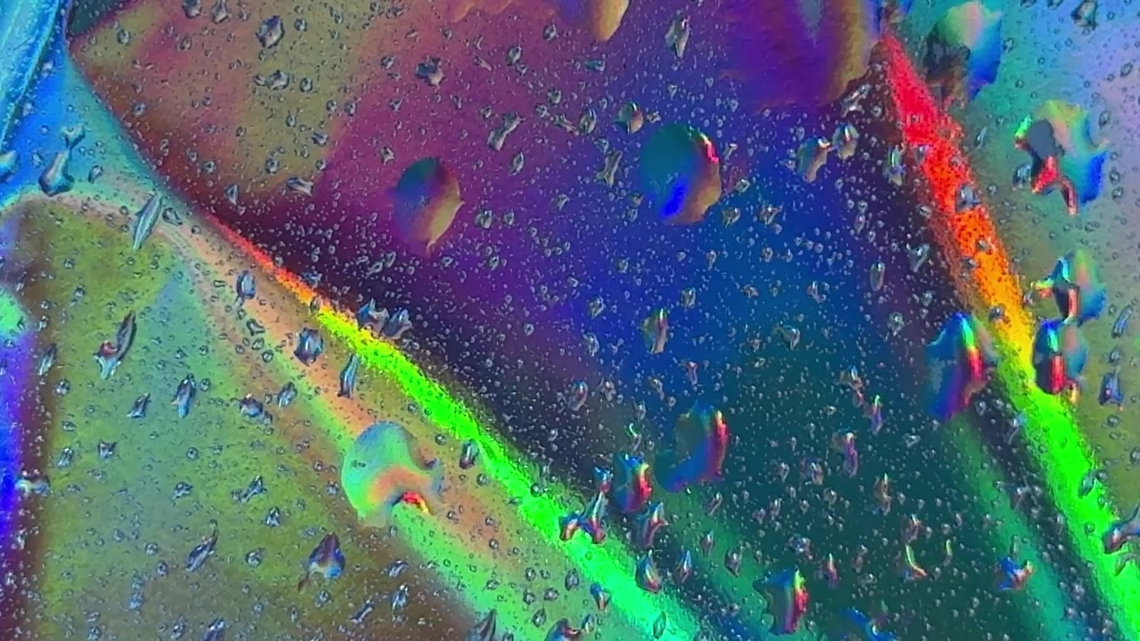 Wassertropfen auf irisierender holografischer Oberfläche