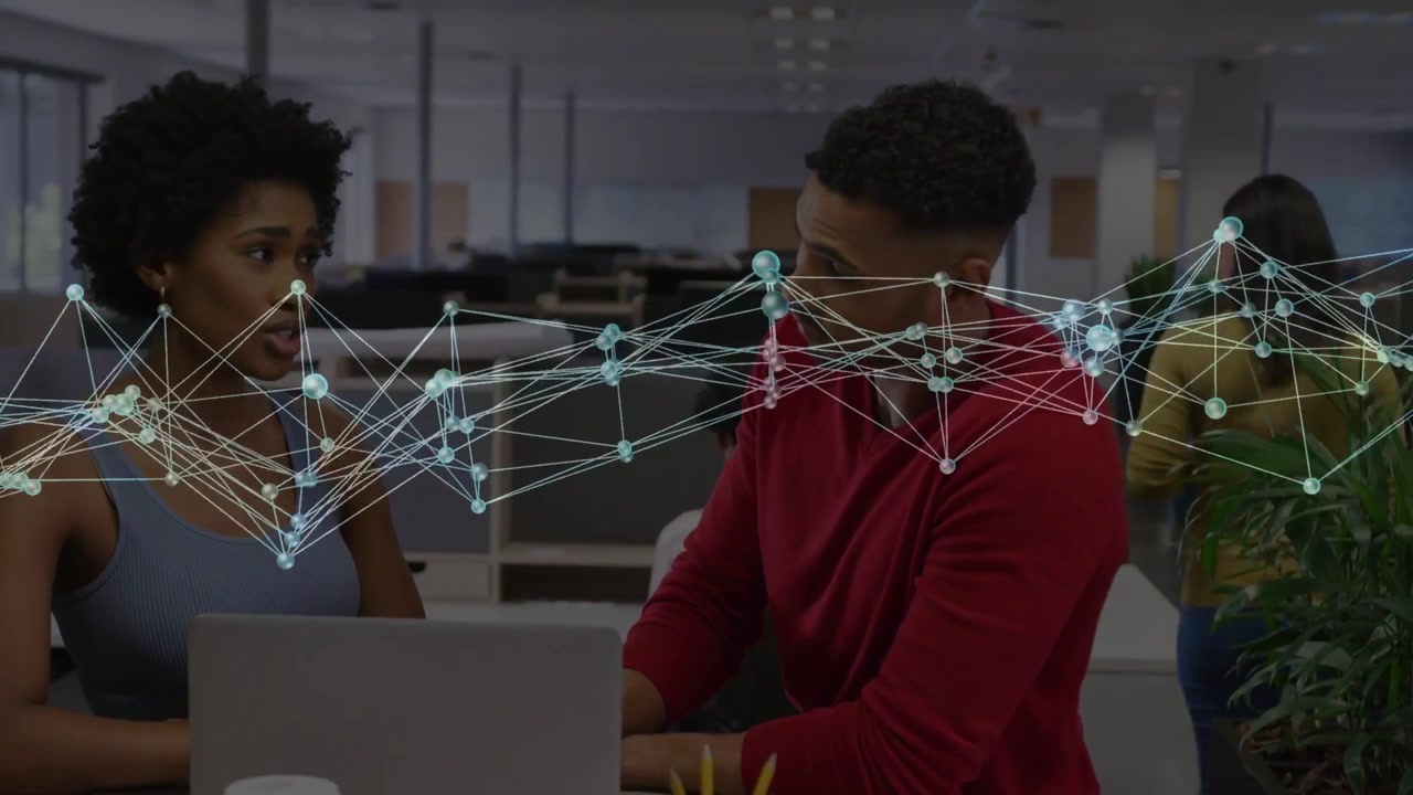 Coworkers working at laptop, man reaching for pencil cup, data overlay guiding business analysis