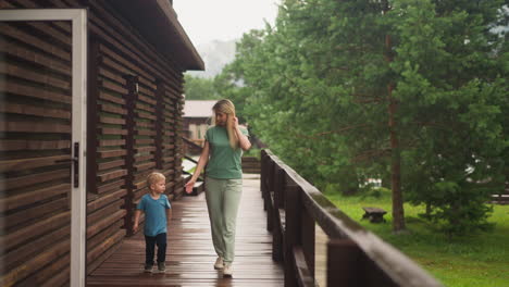 mother gives hand to offended little boy on veranda deck