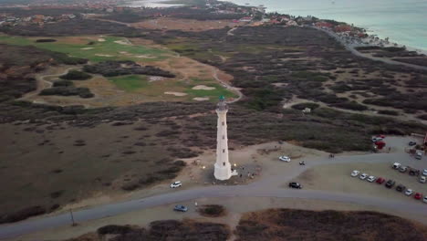 Toma-Aérea-Amplia-Del-Campo-De-Golf-Y-Una-Torre-De-Radio-Detrás-Del-Faro-De-California-En-Noord,-Aruba.