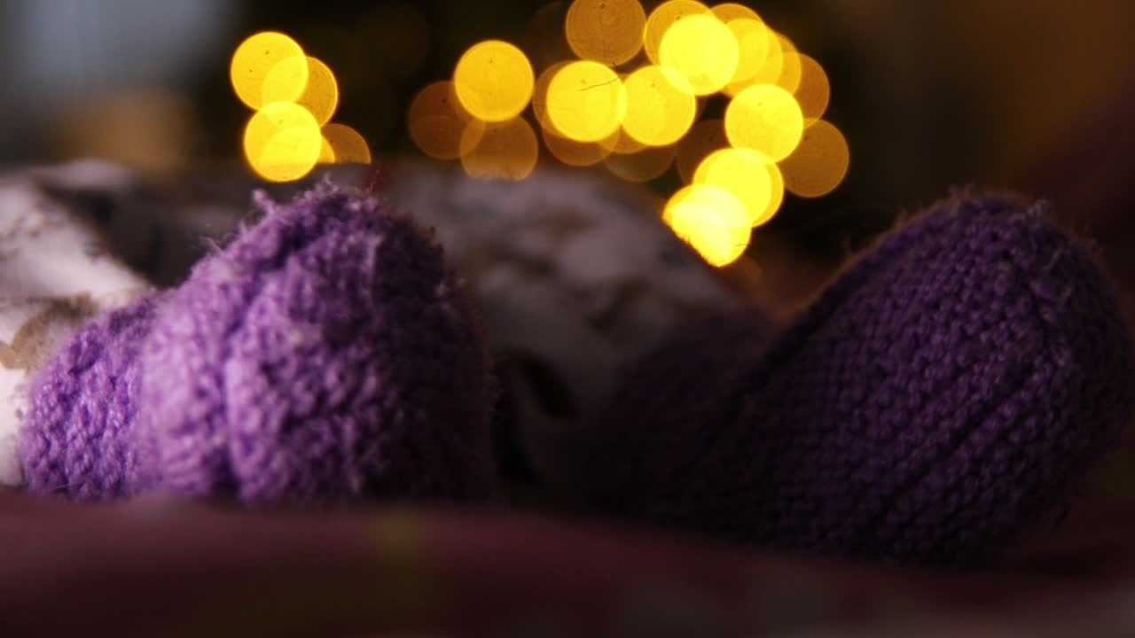 배경에 흐릿한 새해 조명이 있는 보라색 양말을 신은 유아 발