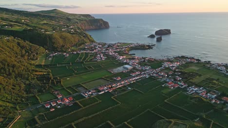 Mosteiros-town-and-coastline-with-lush-green-landscape-at-sunset,-aerial-view