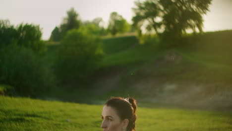 a woman lifts a dumbbell in the park at sunset. back training