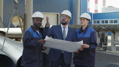 engineer and plant workers discussing blueprint outdoors