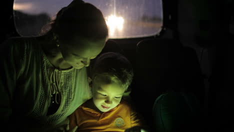 little boy using tablet pc during car travel at night