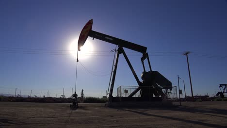 Establishing-shot-of-an-oil-field-with-derricks-pumping-against-the-sun-1