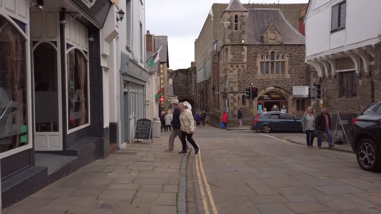 HighStreet in Conwy, Northern Wales. Couples Crossing the riad. another elederly couple with dog.