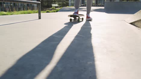 sección baja de hombre caucásico patinando en un skatepark