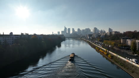 Vista-Aérea-Del-Sena:-París,-Île-De-La-Jatte,-La-Défense,-Barcaza-Bajo-El-Sol.