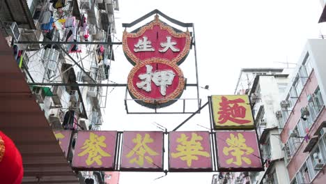 un letrero de neón de una tienda de empeño cuelga de la fachada de un edificio residencial en hong kong