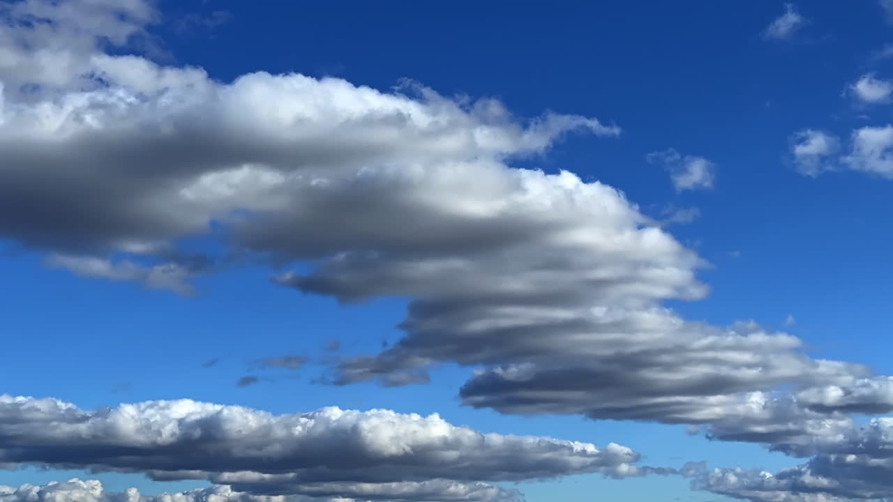 Midday blue sky with clouds. A vast blue sky filled with soft, white clouds drifting slowly under the midday sun, creating a tranquil atmosphere