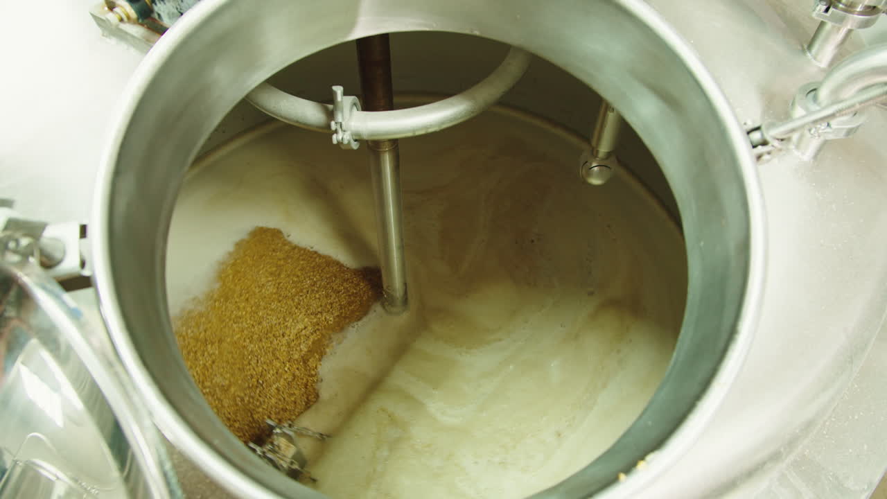 Craft beer production factory, brewery manufacture. Man trying beer in glass close-up. Brewer portrait, cooking alcohol in metal vats bottles