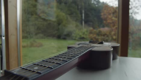 Dolly-forward-along-guitar-on-table-near-window