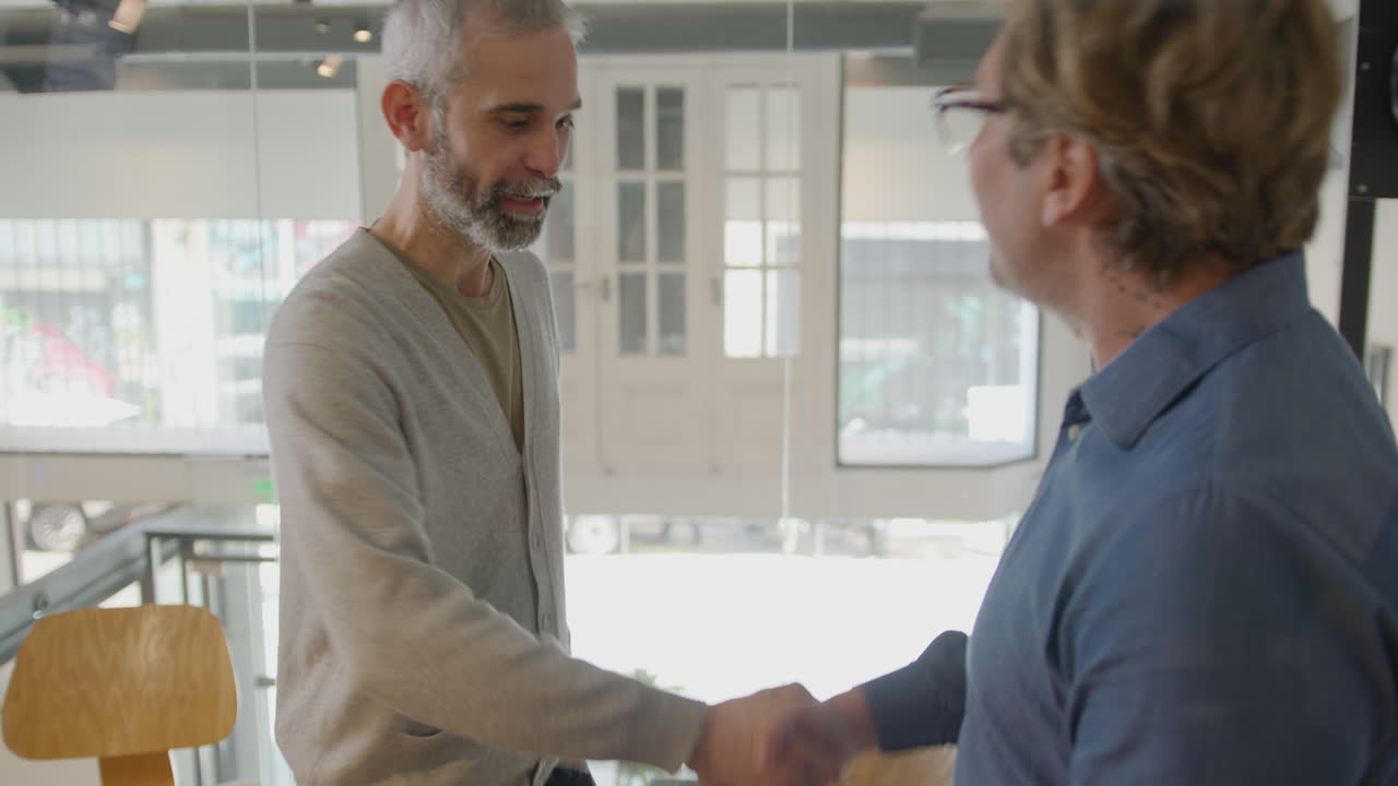 Senior Businessman Greeting Colleague with Handshake in Office