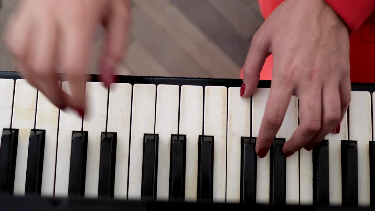 dos manos femeninas con una hermosa manicura roja tocan el piano