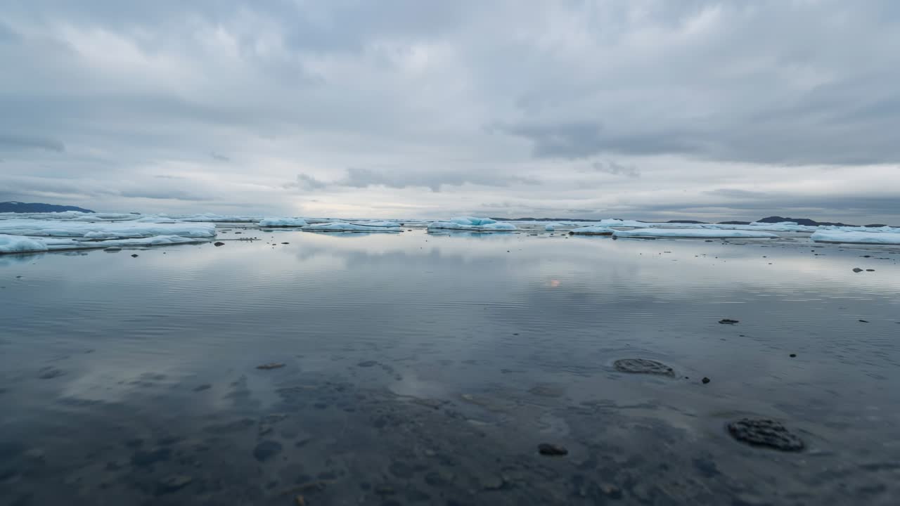 Rippling shallow reflective water revealing pebbled bottom, glacial lagoon wind stirring ice floes