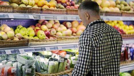 A-middle-aged-shot-assistant-adjusts-the-goods-in-the-window.-Proper-arrangement-of-vegetables-on-the-shelves.-healthy-lifestyle