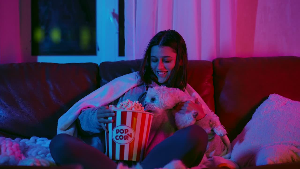 uma rapariga e um cão a desfrutar de uma noite de cinema com pipocas.