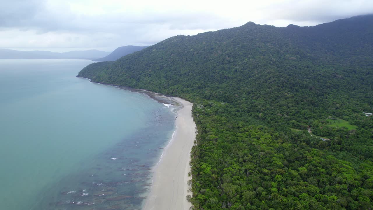 playa de arena blanca con follaje denso tropical y mar azul poco profundo