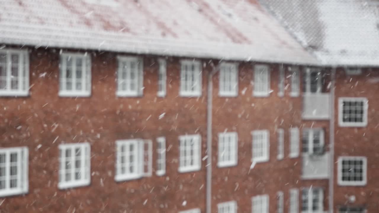 눈송이가 흐릿한 붉은 벽돌집, 겨울날에 떨어지고 있다