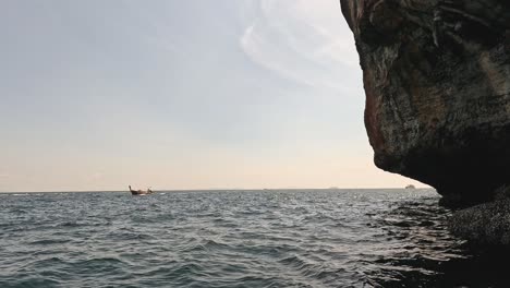 a kayaker paddles near a large rock formation.