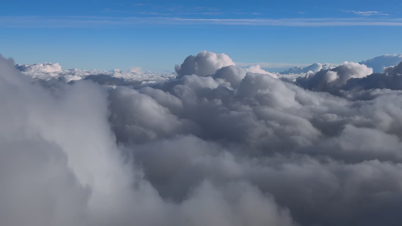 Dreamy Cloudscape captured from a jet cockpit while flying at sunset over an endless blanket of clouds under a blue sky