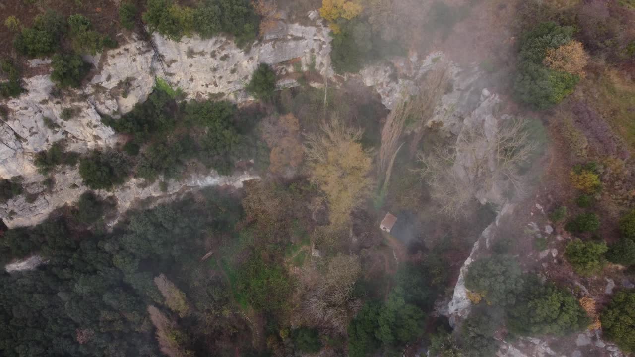 bosque de otoño brumoso y acantilados en osona, barcelona, mostrando una cabaña solitaria, vista aérea