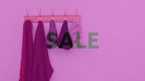 animation of sale text over rack of clothes and hats hanging with pink tint