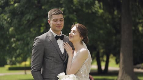 Newlyweds,-caucasian-groom-with-bride-walking,-embracing,-hugs-in-park,-wedding-couple