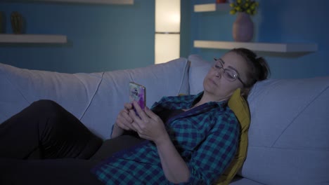 mujer durmiendo por la noche con el teléfono en la mano. adicción al teléfono.