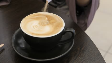 person stirring a latte in a black cup