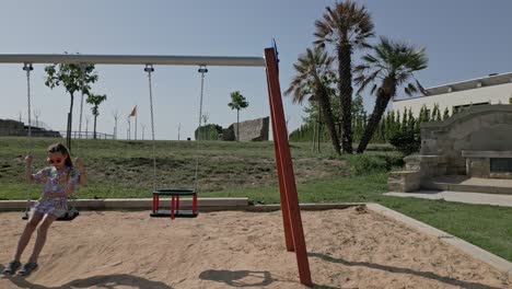 little caucasian girl swings playground hammocks spain countryside panoramic view, calders, catalonia, barcelona