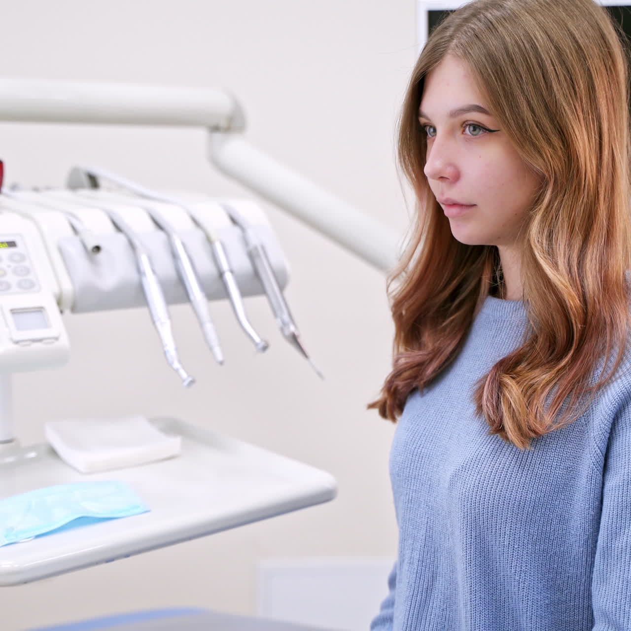 Young woman eats an apple in modern dental clinic. Healthy teeth concept. Solving sensitive teeth problem.