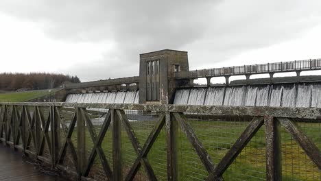 Staudammtor-Des-Llyn-Cefni-Stausees,-Der-Aus-Der-Lagune-Von-Llangefni-überläuft-Und-Von-Holzzäunen-Umgeben-Ist