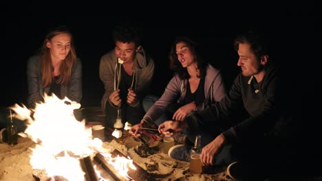 Beach-party-late-at-night-with-bonfire-and-roasting-marsh-mellows-with-friends