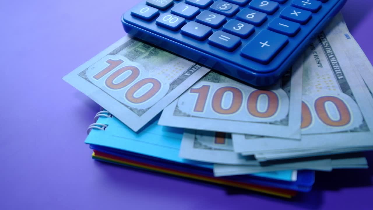 calculadora y dinero sobre un fondo púrpura