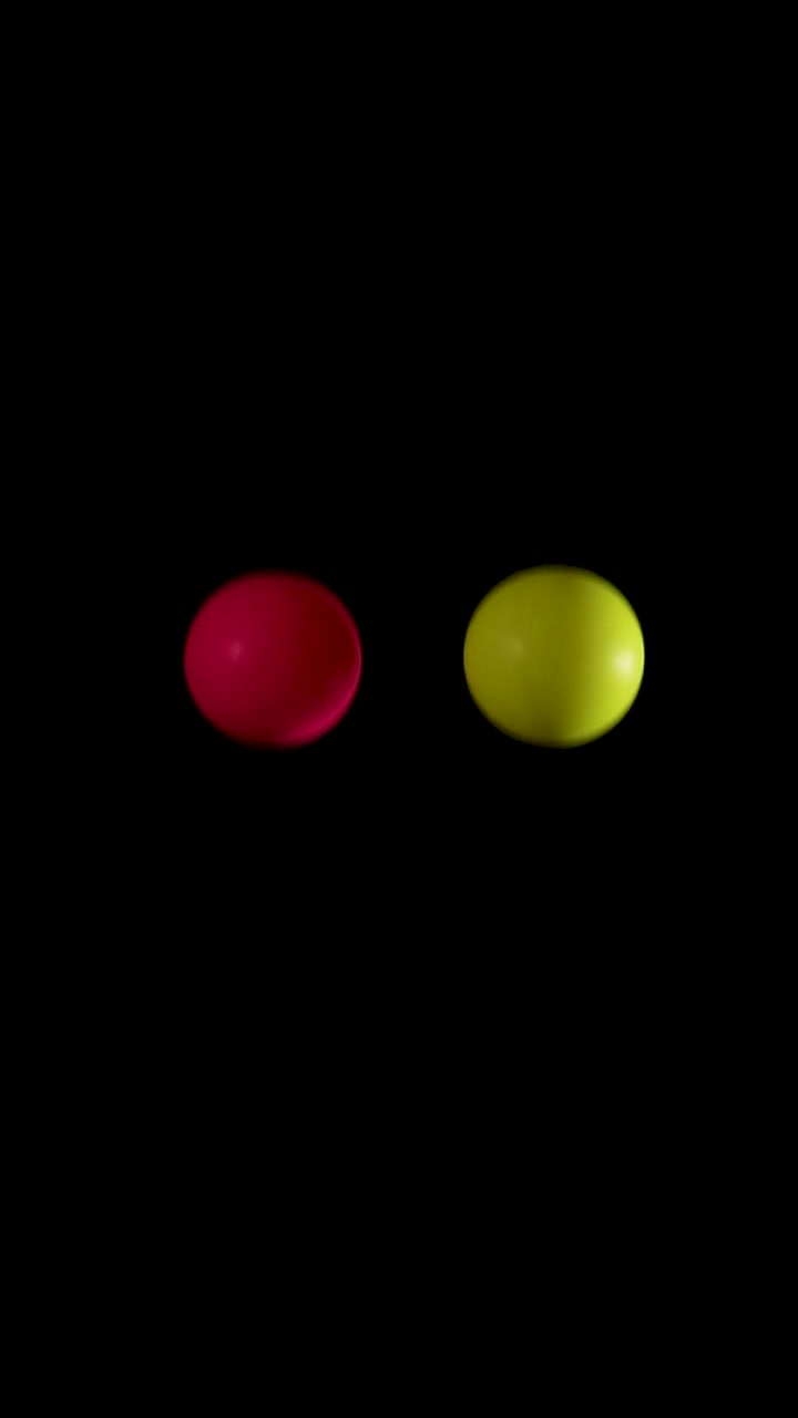Vivaci palline rosa e gialle cadono e rimbalzano su uno sfondo nero uniforme, formato verticale