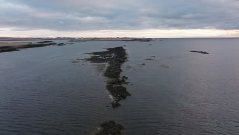 aerial view of the rocky coastline stretching into the ocean near akranes, iceland, beneath a cloudy sky with a calm sea